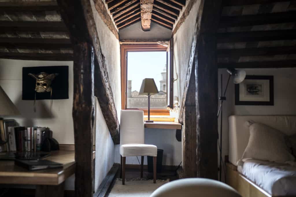 Open space with small studio with chair and wooden beams - Altana Studio Apartment Open space with small studio with chair and wooden beams - Altana Studio Apartment