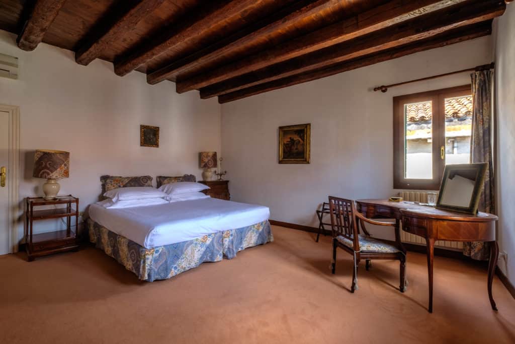 Large double bedroom with small antique desk and exposed beams - Ca' Affresco 1 Apartment Large double bedroom with small antique desk and exposed beams - Ca' Affresco 1 Apartment