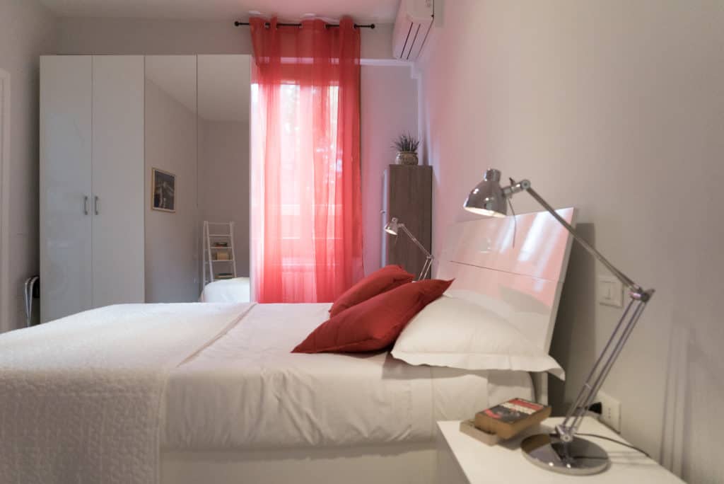 Left side of the bedroom with red curtains and modern furnishing - Venier Apartment Left side of the bedroom with red curtains and modern furnishing - Venier Apartment