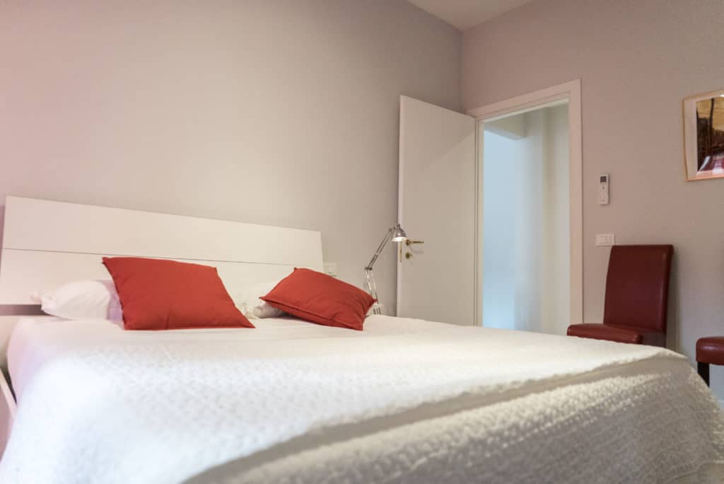 Modern double bedroom with red pillows - Venier Apartment Modern double bedroom with red pillows - Venier Apartment