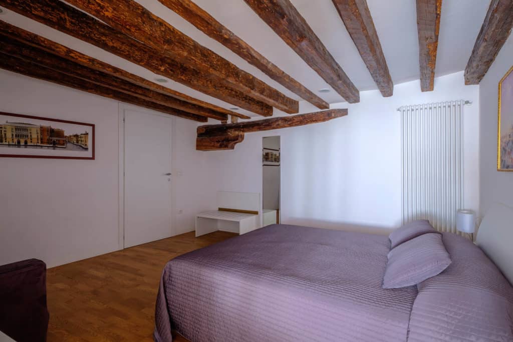 Left view of the luminous master bedroom with exposed beams and sofa - The Lion's 5 Apartment Left view of the luminous master bedroom with exposed beams and sofa - The Lion's 5 Apartment