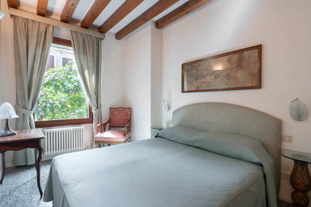Left view of the luminous small master bedroom with vintage furn