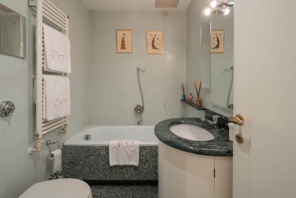 Small bathroom with marbled sink and tub - Garden Apartment