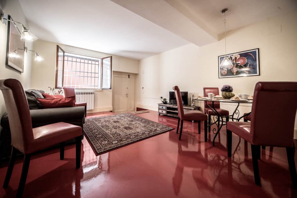 Large living room with red floor and small dining table - Kandinskij House Apartment